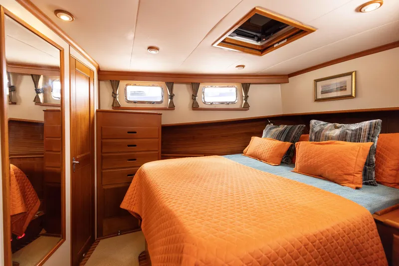 Slide: The Image of Luxurious 2005 Grand Banks Europa cabin with orange bedding and wooden interior. - 19