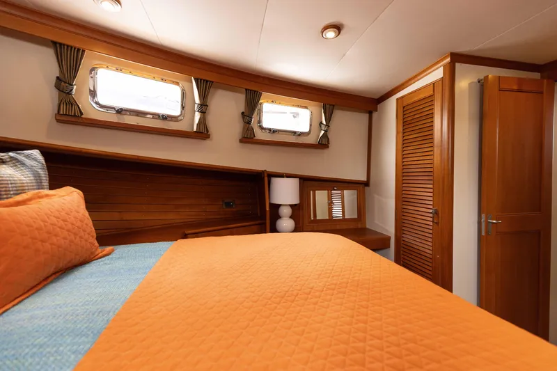 Slide: The Image of Luxurious 2005 Grand Banks Europa cabin with orange bedding and wooden accents. - 20
