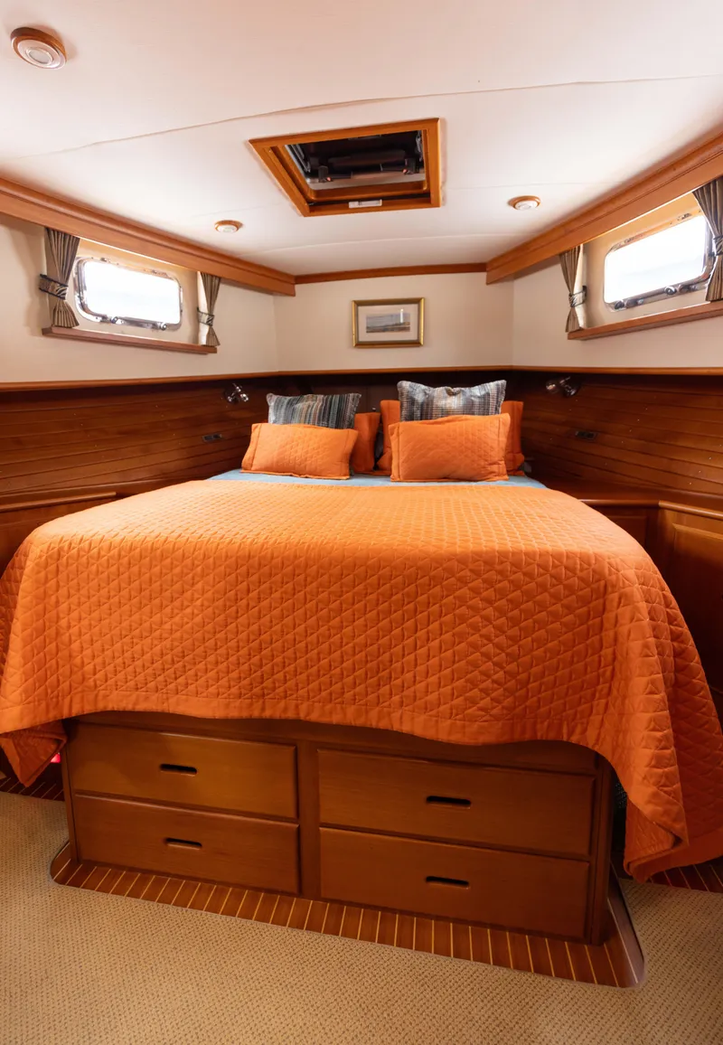 Slide: The Image of Cozy bedroom in 2005 Grand Banks Europa yacht with orange bedding and wooden accents. - 21