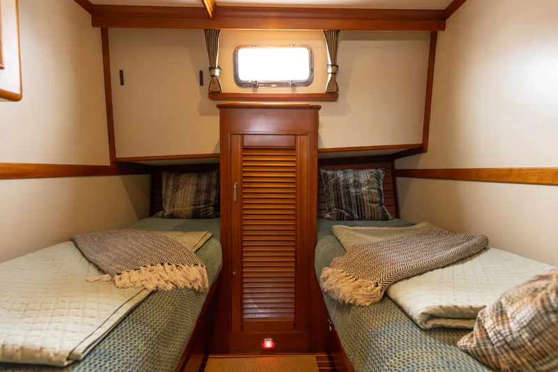 Slide: The Image of Cozy twin cabin in 2005 Grand Banks Europa yacht with wooden accents and soft bedding. - 25