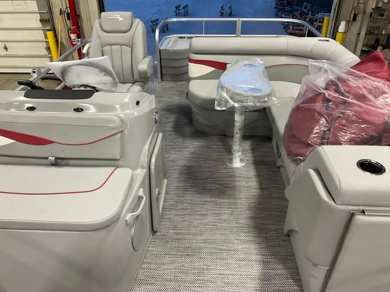 Slide: The Image of 2023 Bennington 20SVF pontoon boat interior with gray and red seating, table, and helm. - 10