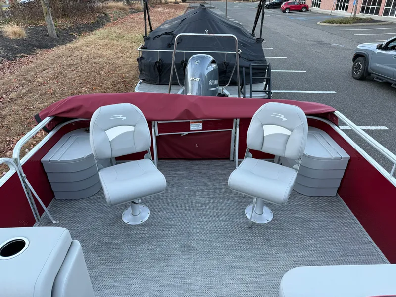Slide: The Image of 2023 Bennington 20SVF pontoon boat with red and gray seating in a parking lot. - 22