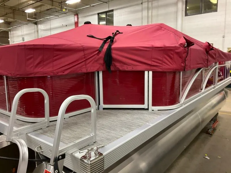 Slide: The Image of 2023 Bennington 20SVF pontoon boat with red cover in a warehouse setting. - 3