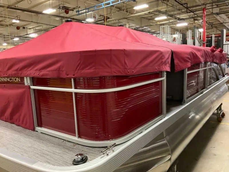 Slide: The Image of 2023 Bennington 20SVF pontoon boat with red cover in a warehouse setting. - 4