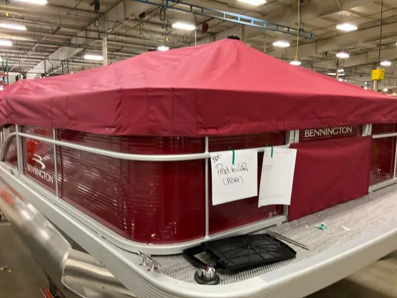 Slide: The Image of 2023 Bennington 20SVF pontoon boat with red cover in a warehouse setting. - 5