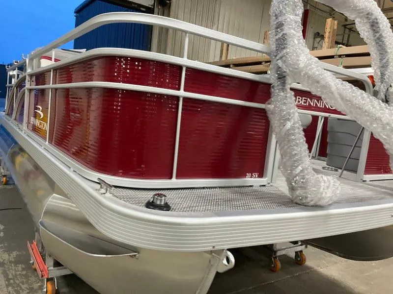 Slide: The Image of 2023 Bennington 20SVF pontoon boat with red exterior, docked indoors. - 9