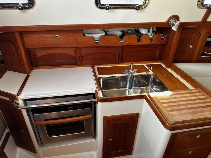 Slide: The Image of Galley of 2006 Pacific Seacraft 31 sailboat with stove, sink, and wooden cabinetry. - 10