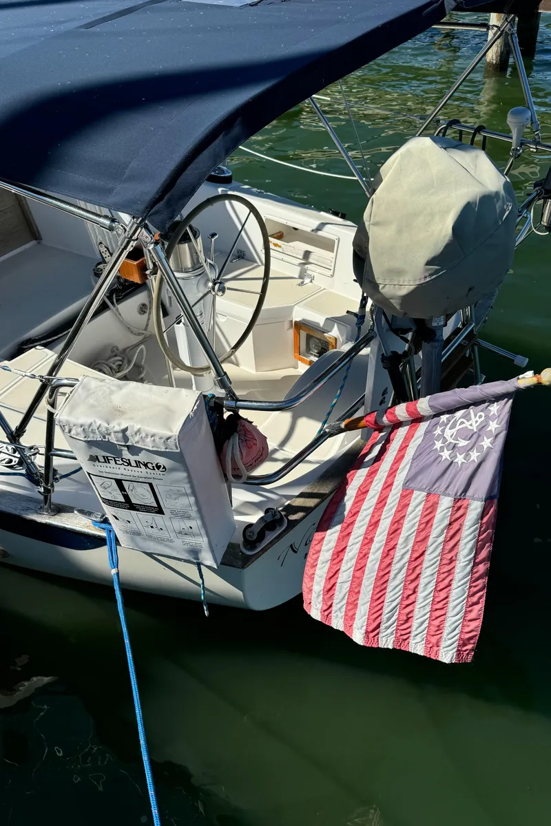 Slide: The Image of 2006 Pacific Seacraft 31 sailboat with American flag, docked in calm waters. - 6