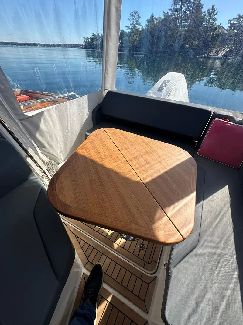 Slide: The Image of Cozy seating area on 2021 Nimbus W9 boat with wooden table and scenic lake view. - 29