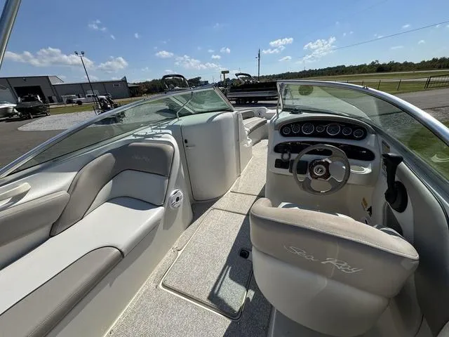 Slide: The Image of 2002 Sea Ray 240 Sundeck interior with seating and dashboard, parked outdoors. - 7