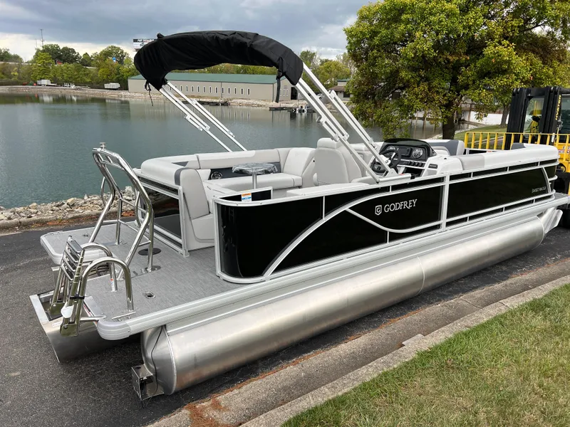 Slide: The Image of 2025 Godfrey Sweetwater 2286 C Special Edition pontoon boat docked by a serene lake. - 4