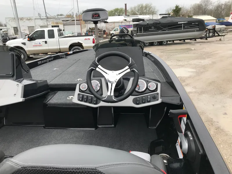 Slide: The Image of 2025 Ranger Z185 boat cockpit with steering wheel and control panel, parked outdoors. - 15