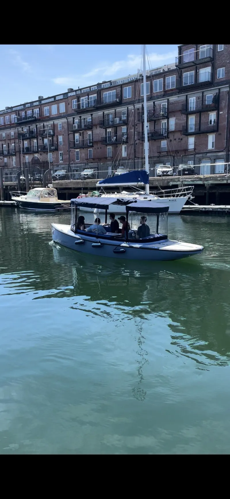 Slide: The Image of 2024 Vision Marine Technologies Fantail 217 boat cruising in a harbor with buildings in the background. - 3