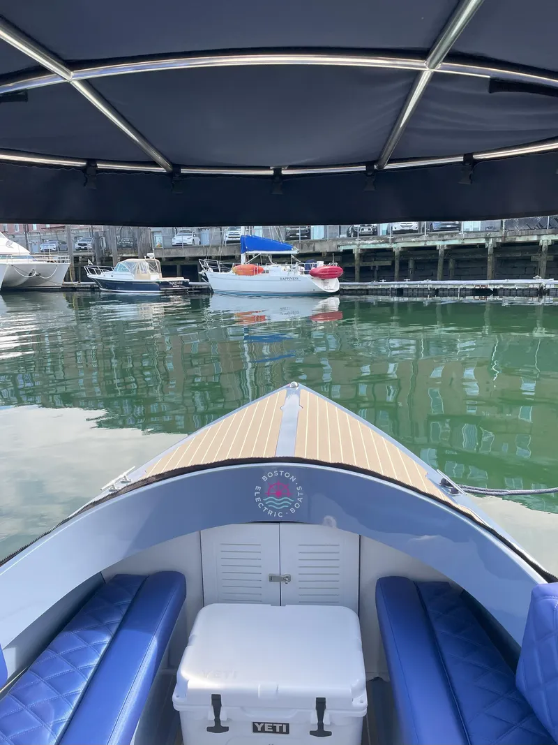 Slide: The Image of 2024 Vision Marine Technologies Fantail 217 boat interior with blue seating and canopy on calm water. - 8