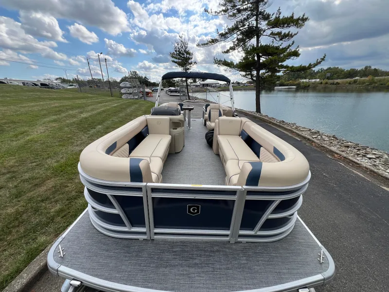 Slide: The Image of 2025 Godfrey SWEETWATER 2286 SB pontoon boat docked by a scenic lakeside. - 10