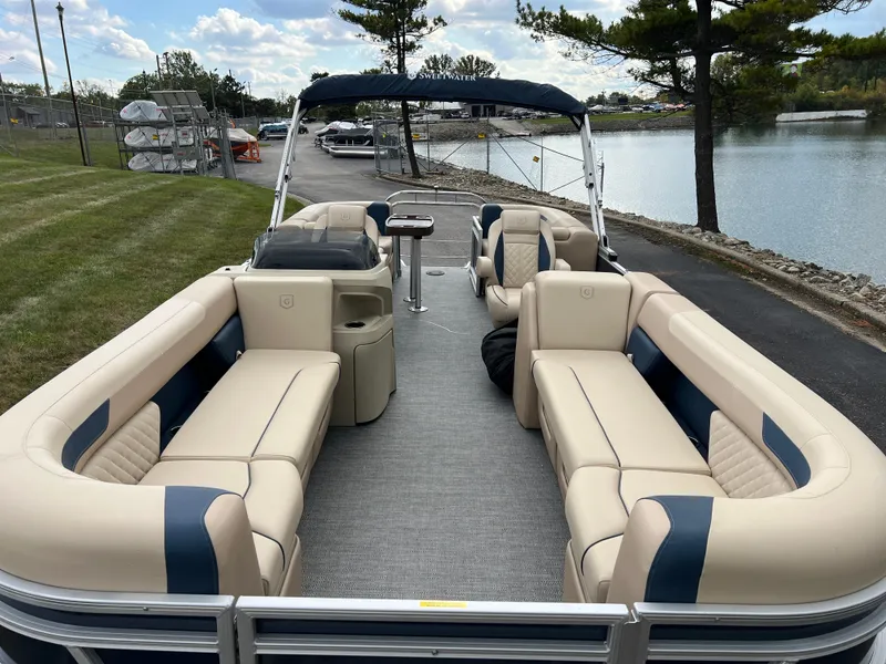 Slide: The Image of 2025 Godfrey SWEETWATER 2286 SB pontoon boat with spacious seating, docked by a serene lake. - 11