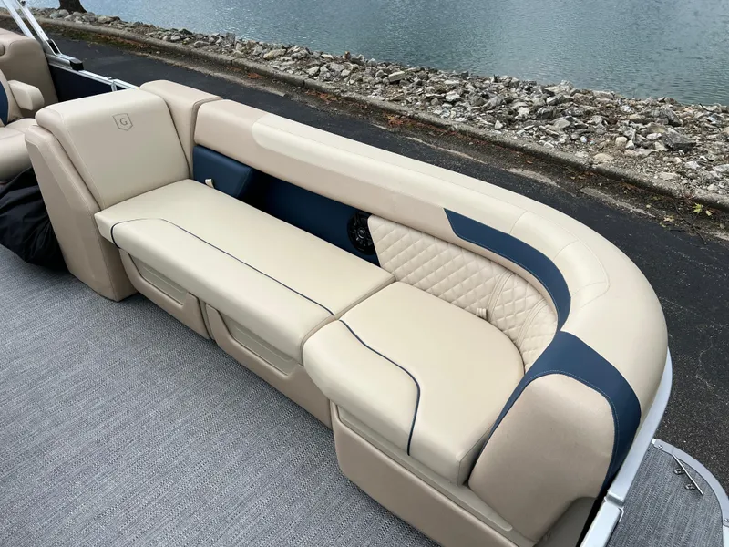 Slide: The Image of 2025 Godfrey SWEETWATER 2286 SB boat seating with beige and blue upholstery by the water. - 13