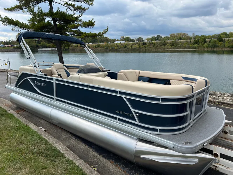 Slide: The Image of 2025 Godfrey SWEETWATER 2286 SB pontoon boat docked by a scenic lake. - 3
