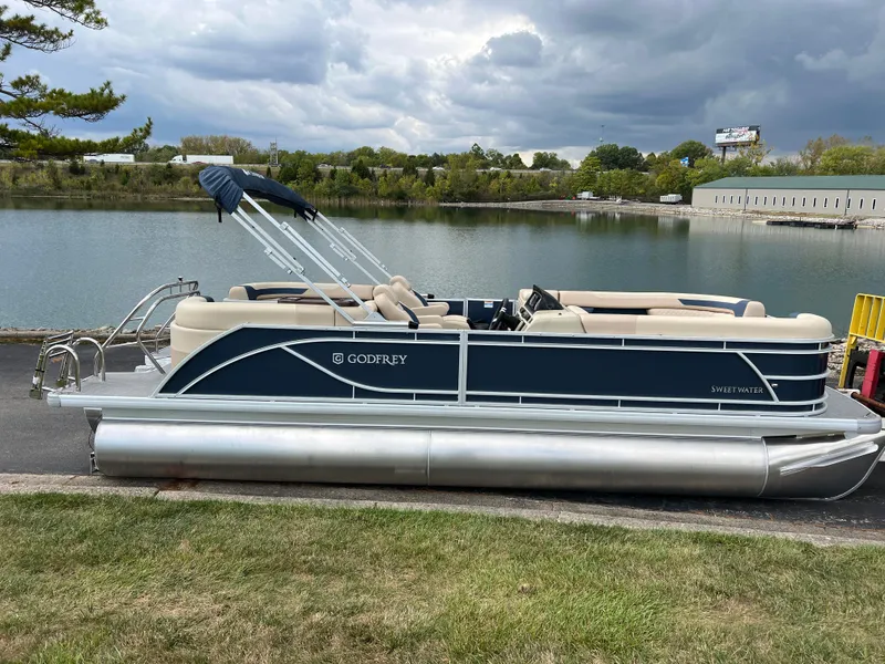 Slide: The Image of 2025 Godfrey SWEETWATER 2286 SB pontoon boat docked by a serene lake. - 4