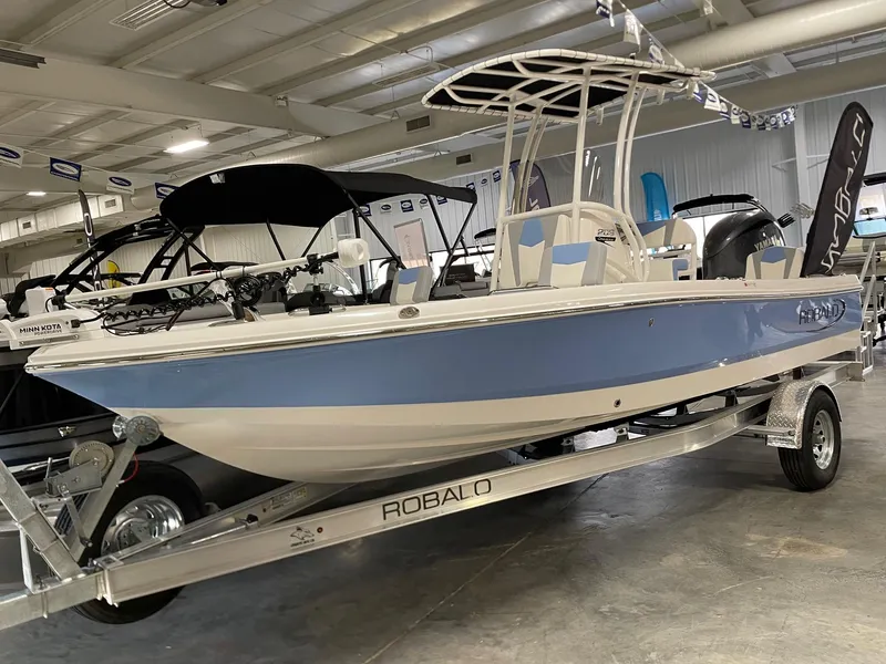 The Image of 2025 Robalo 206 Cayman boat in showroom, blue and white design on trailer. - 0