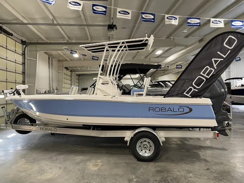 Slide: The Image of 2025 Robalo 206 Cayman boat in showroom, side view with blue and white design. - 2