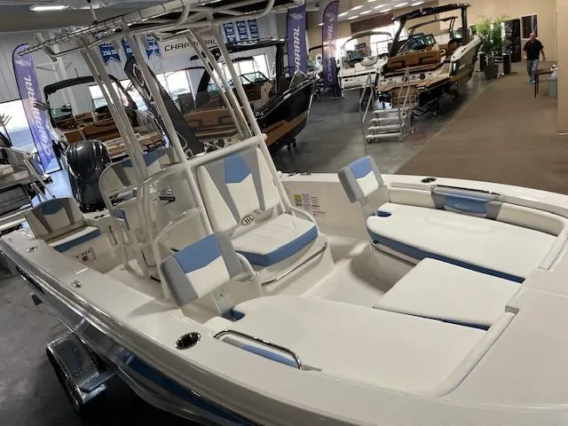 Slide: The Image of 2025 Robalo 206 Cayman boat interior at a showroom, featuring white and blue seating. - 3