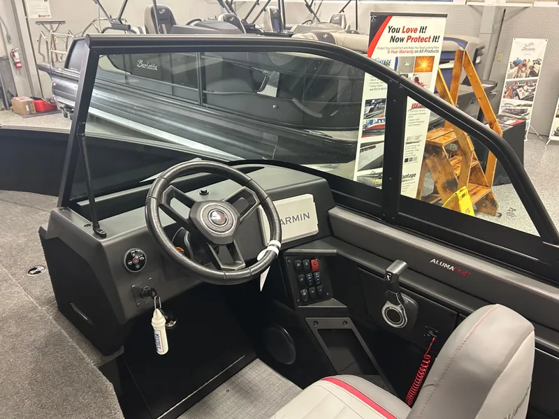 Slide: The Image of 2025 Alumacraft Trophy 185X Sport boat interior with steering wheel and Garmin display. - 11