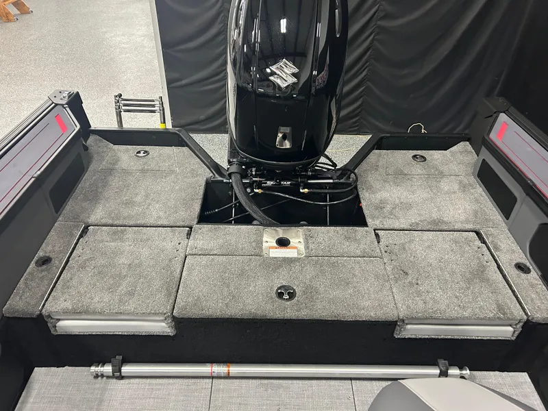 Slide: The Image of 2025 Alumacraft Trophy 185X Sport boat interior with motor and storage compartments. - 13