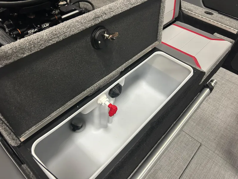 Slide: The Image of 2025 Alumacraft Trophy 185X Sport boat storage compartment with gray interior and red accents. - 15