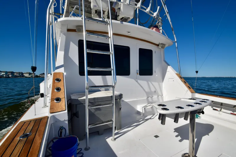 Slide: The Image of 1982 Bertram 46 Convertible yacht deck with fishing setup on calm water. - 26