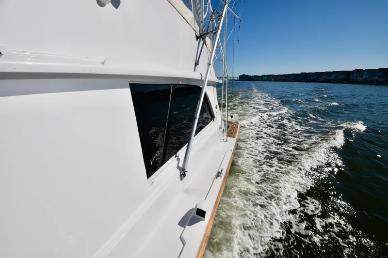 Slide: The Image of 1982 Bertram 46 Convertible cruising on open water under clear blue sky. - 32