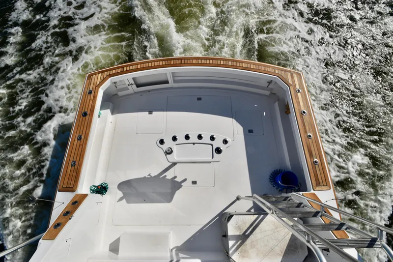 Slide: The Image of 1982 Bertram 46 Convertible boat deck with wooden trim, cruising through water. - 37