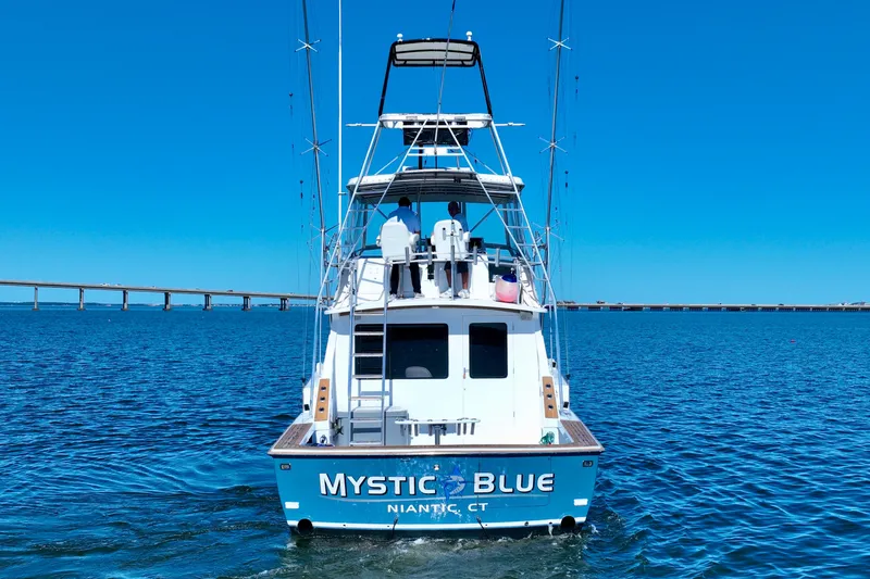 Slide: The Image of 1982 Bertram 46 Convertible boat "Mystic Blue" on open water, clear sky background. - 4