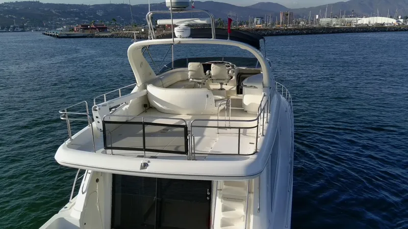 Slide: The Image of 2004 Meridian 580 Pilothouse yacht on water, featuring spacious deck and scenic harbor backdrop. - 18