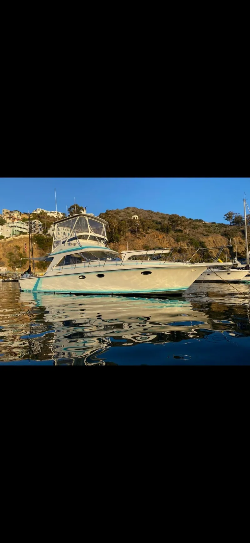 Slide: The Image of 1988 Trojan 12 Meter Convertible yacht docked at marina under clear blue sky. - 4