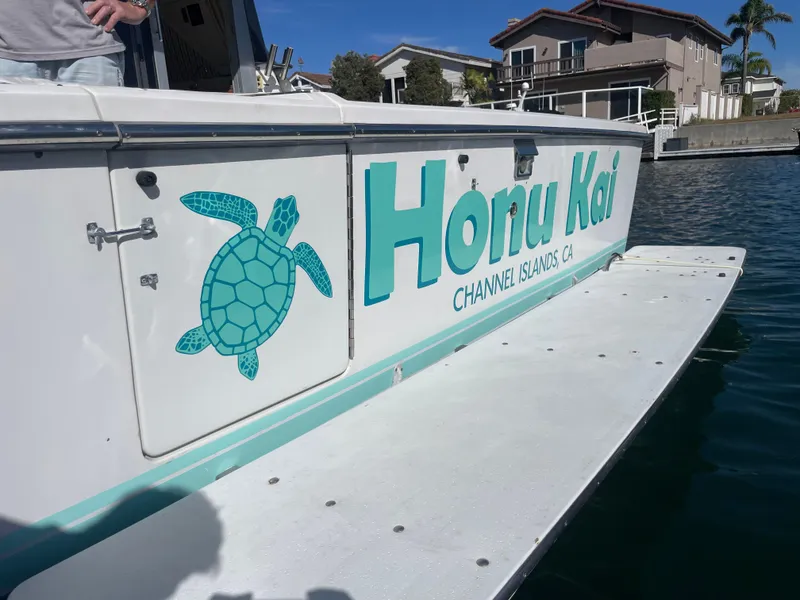 Slide: The Image of 1988 Trojan 12 Meter Convertible yacht docked at marina, featuring "Honu Kai" branding. - 5