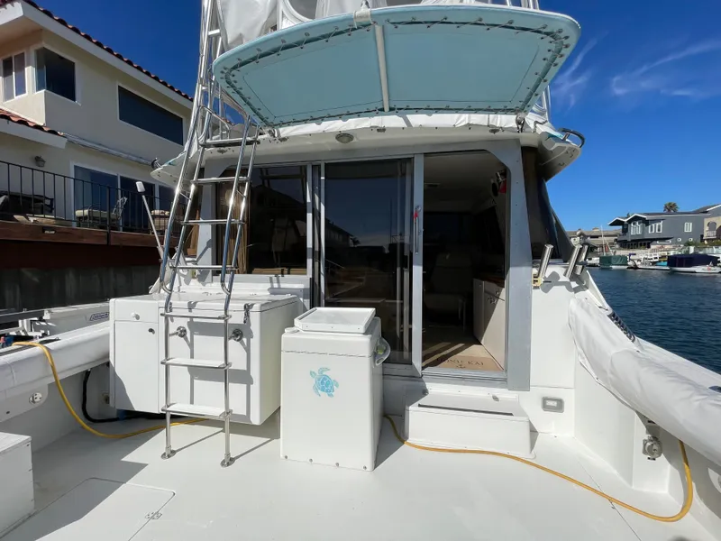 Slide: The Image of 1988 Trojan 12 Meter Convertible boat deck, spacious and clean, docked by waterfront homes. - 10
