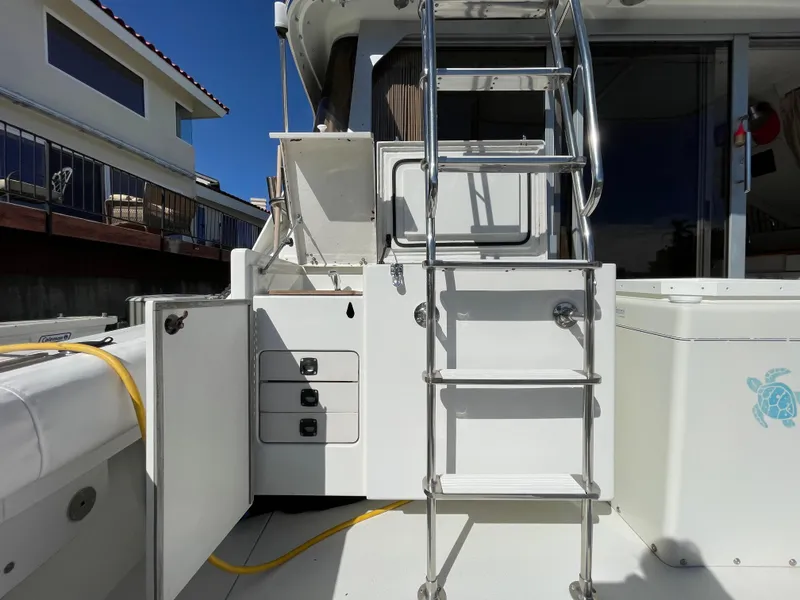 Slide: The Image of 1988 Trojan 12 Meter Convertible boat deck, spacious and clean, docked by the water. - 12