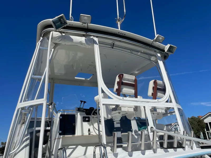 Slide: The Image of 1988 Trojan 12 Meter Convertible yacht docked, featuring spacious deck and ladder. - 14