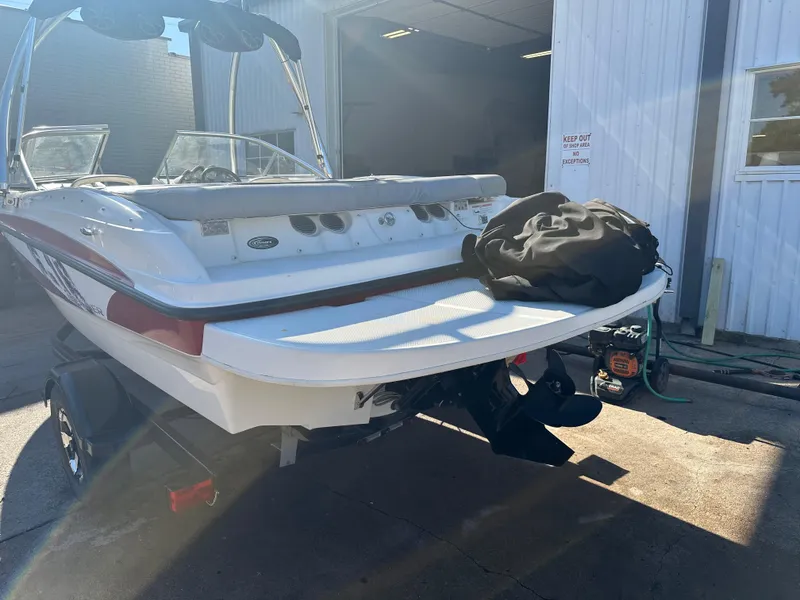 Slide: The Image of 2011 Bayliner 185 boat on trailer, parked outside a garage in sunlight. - 14