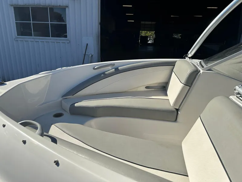 Slide: The Image of 2011 Bayliner 185 boat interior with cushioned seating in a sunlit setting. - 16