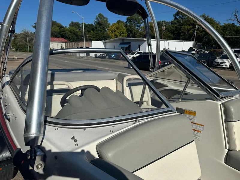 Slide: The Image of 2011 Bayliner 185 boat interior with steering wheel and seating, parked outdoors. - 19