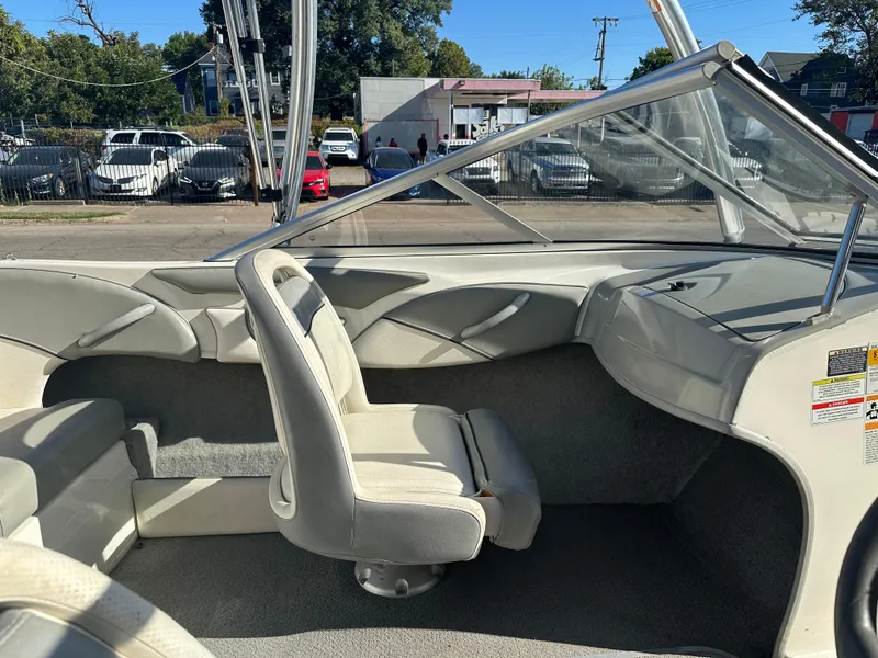 Slide: The Image of 2011 Bayliner 185 boat interior with seating and dashboard, parked outdoors. - 25