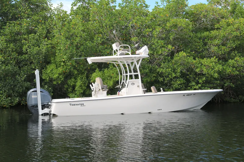 The Image of 2021 Tidewater 2500 Carolina Bay boat on calm water, surrounded by lush greenery. - 0