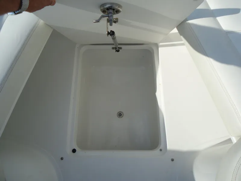 Slide: The Image of Storage compartment on a 2007 Cobalt 302 boat, featuring a drain and latch. - 26