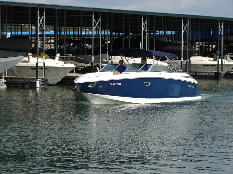Slide: The Image of 2007 Cobalt 302 boat cruising near a marina with covered docks. - 28