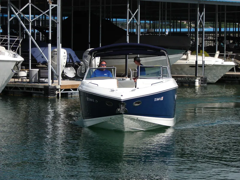 Slide: The Image of 2007 Cobalt 302 boat navigating marina waters, docked boats in background. - 30