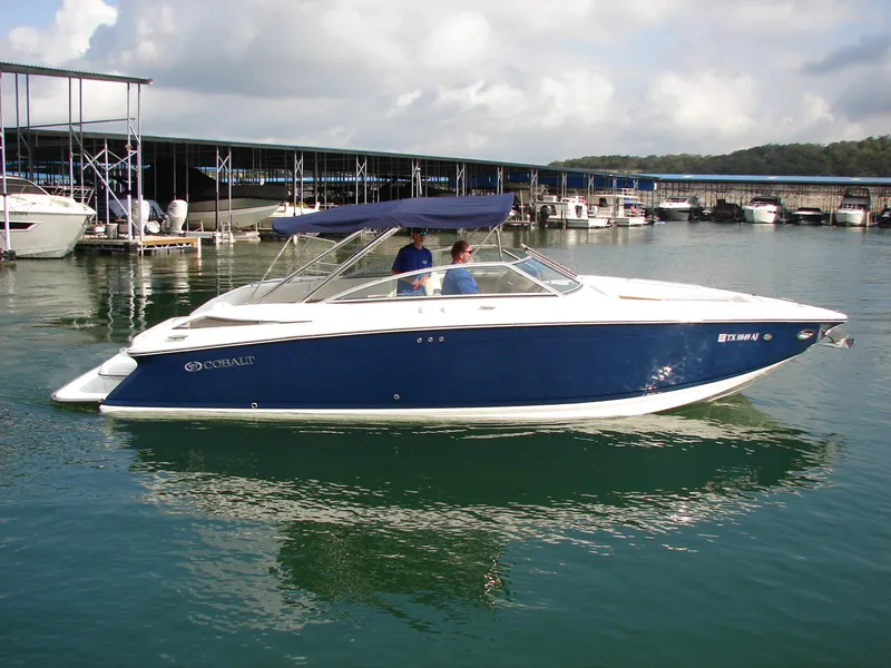 Slide: The Image of 2007 Cobalt 302 boat docked on calm water with blue canopy. - 34