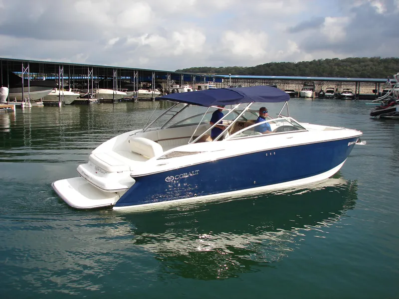 Slide: The Image of 2007 Cobalt 302 boat on calm water near a marina, featuring a blue and white design. - 35