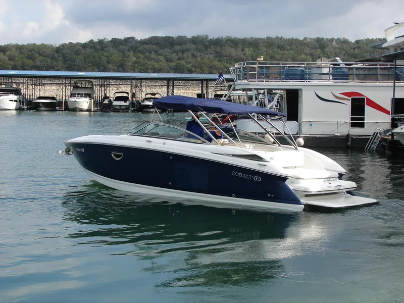 Slide: The Image of 2007 Cobalt 302 boat docked in a marina, featuring a sleek blue and white design. - 38